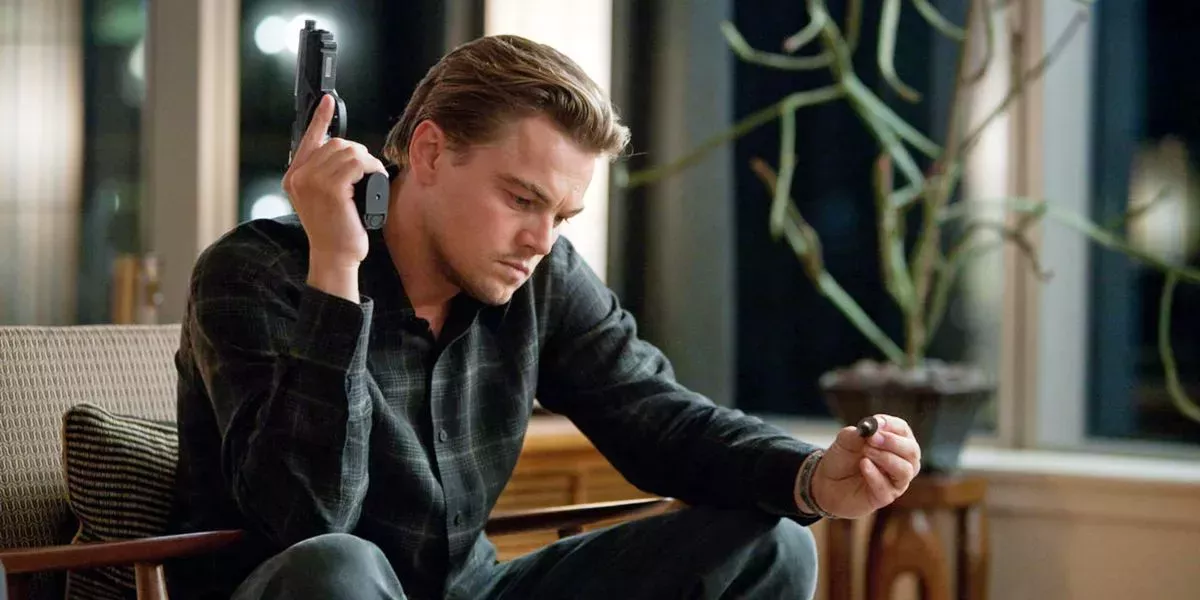 Leonardo DiCaprio staring at his totem with gun in hand in Inception