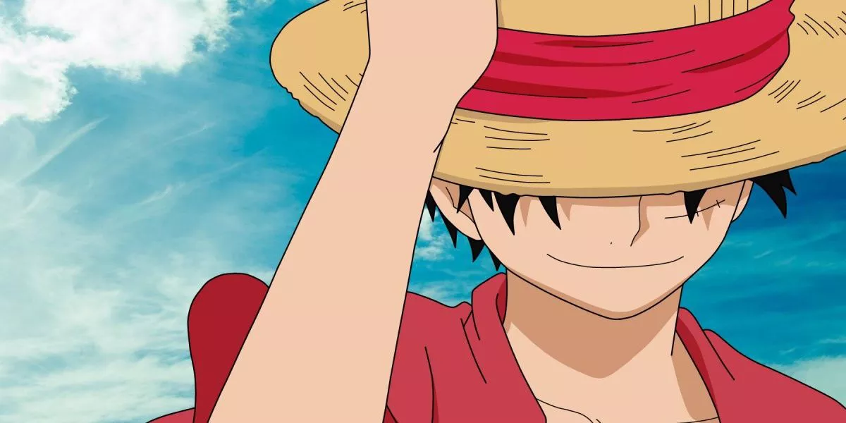 Monkey D. Luffy holding his iconic Straw Hat and smiling during One Piece