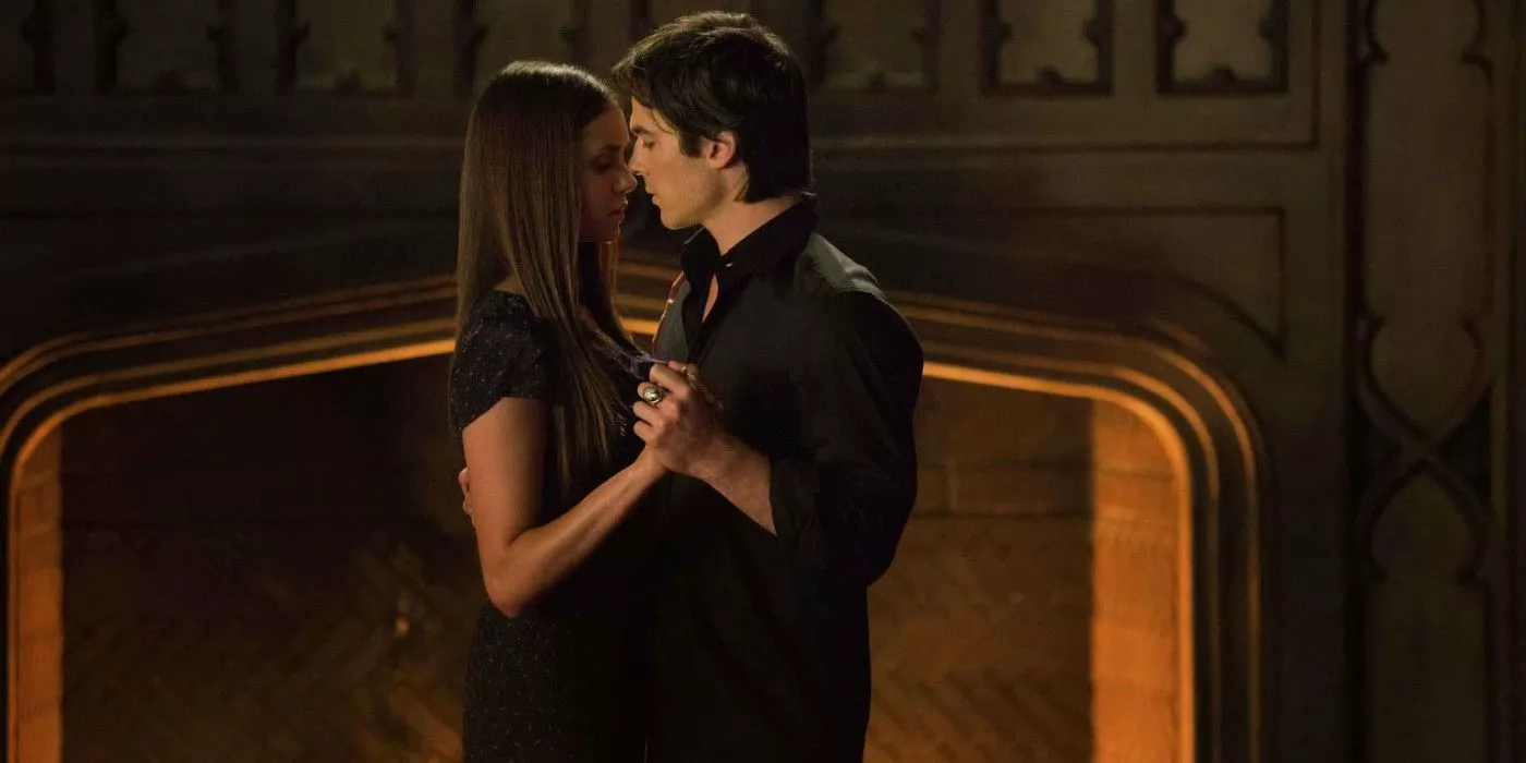 Damon y Elena bailando cerca de una chimenea en The Vampire Diaries.