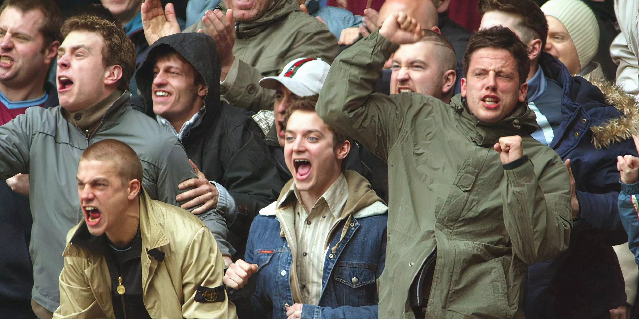 Charlie Hunnam y Elijah Wood animando a un grupo de personas en un partido de fútbol en Green Street Hooligans.