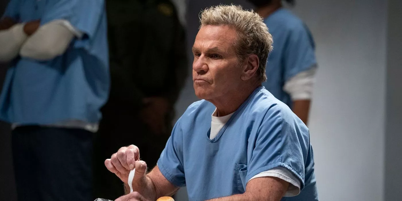 John Kreese in a blue prison uniform holding a plastic spoon in Cobra Kai Season 5.