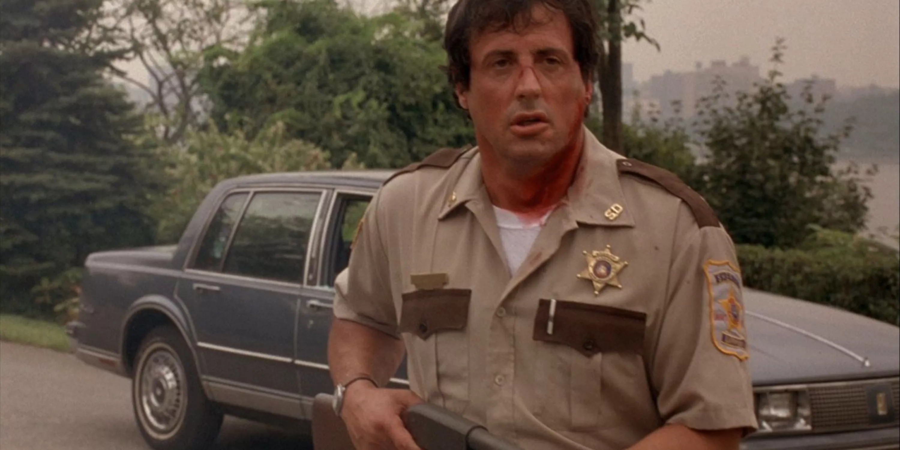 Sylvester Stallone as Freddy Heflin in Cop Land stands in front of car