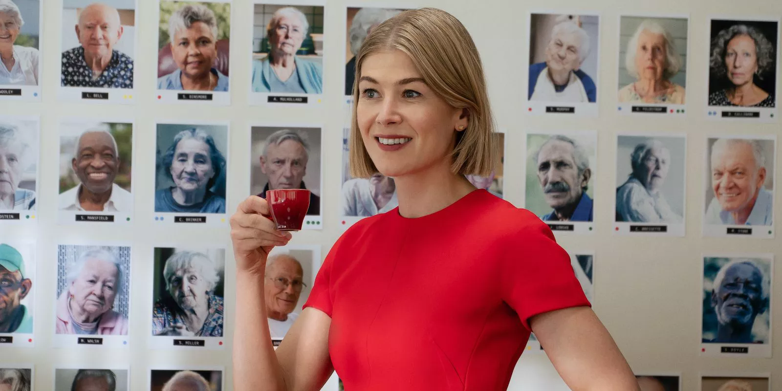 Rosamund Pike lleva un vestido rojo y bebe café en Me Importa Un Carajo