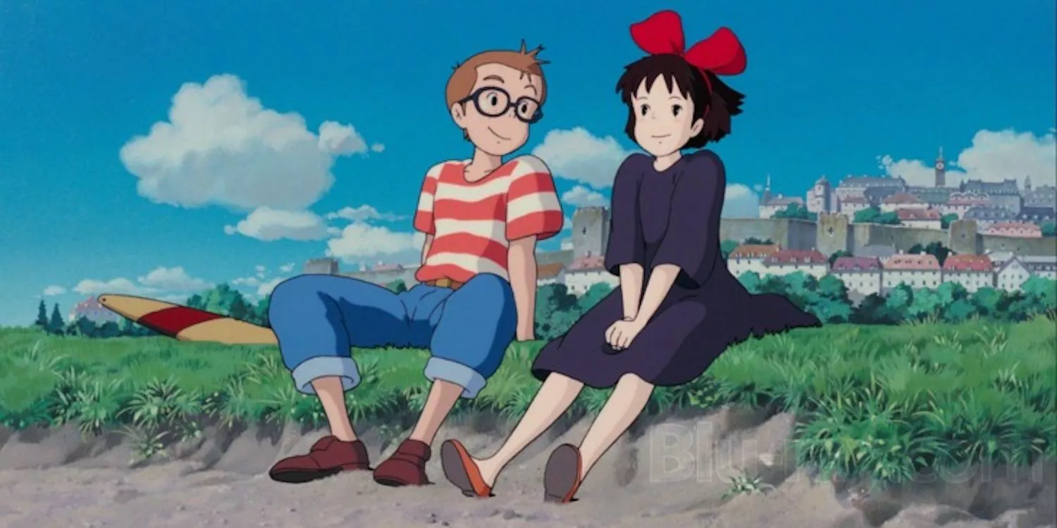 Kiki in a black dress and Tombo in a striped sweater sit on the beach in Kiki's Delivery Service