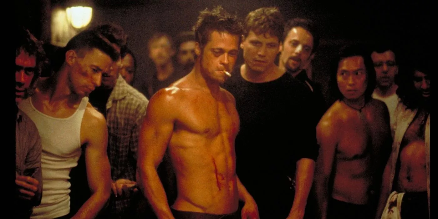 Brad Pitt como un Tyler Durden sin camisa, rodeado de personas en la película Fight Club.