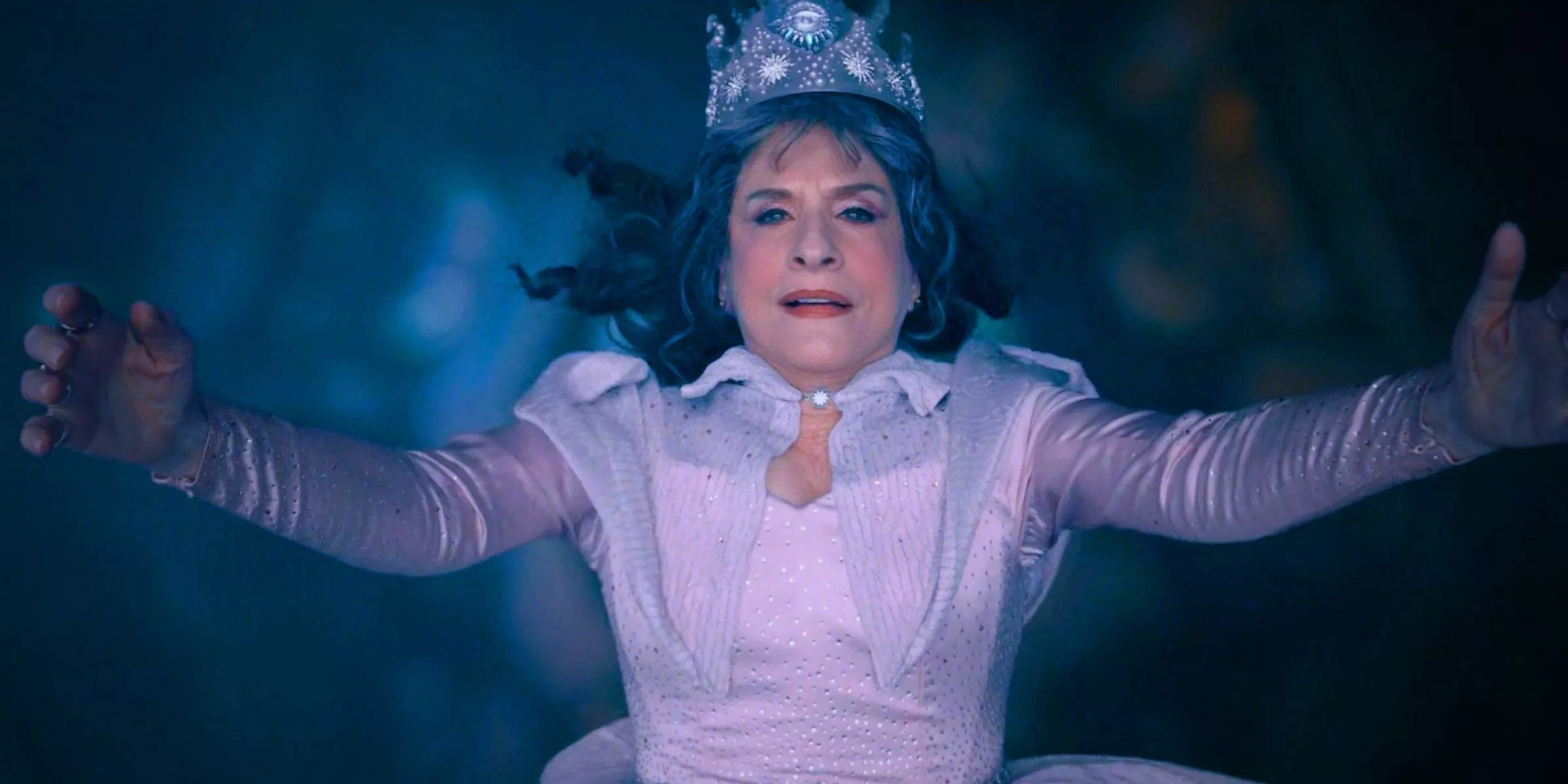 Patti Lupone as Lilia Calderu in a princess dress and crown falling with a peaceful look her face in Agatha All Along.