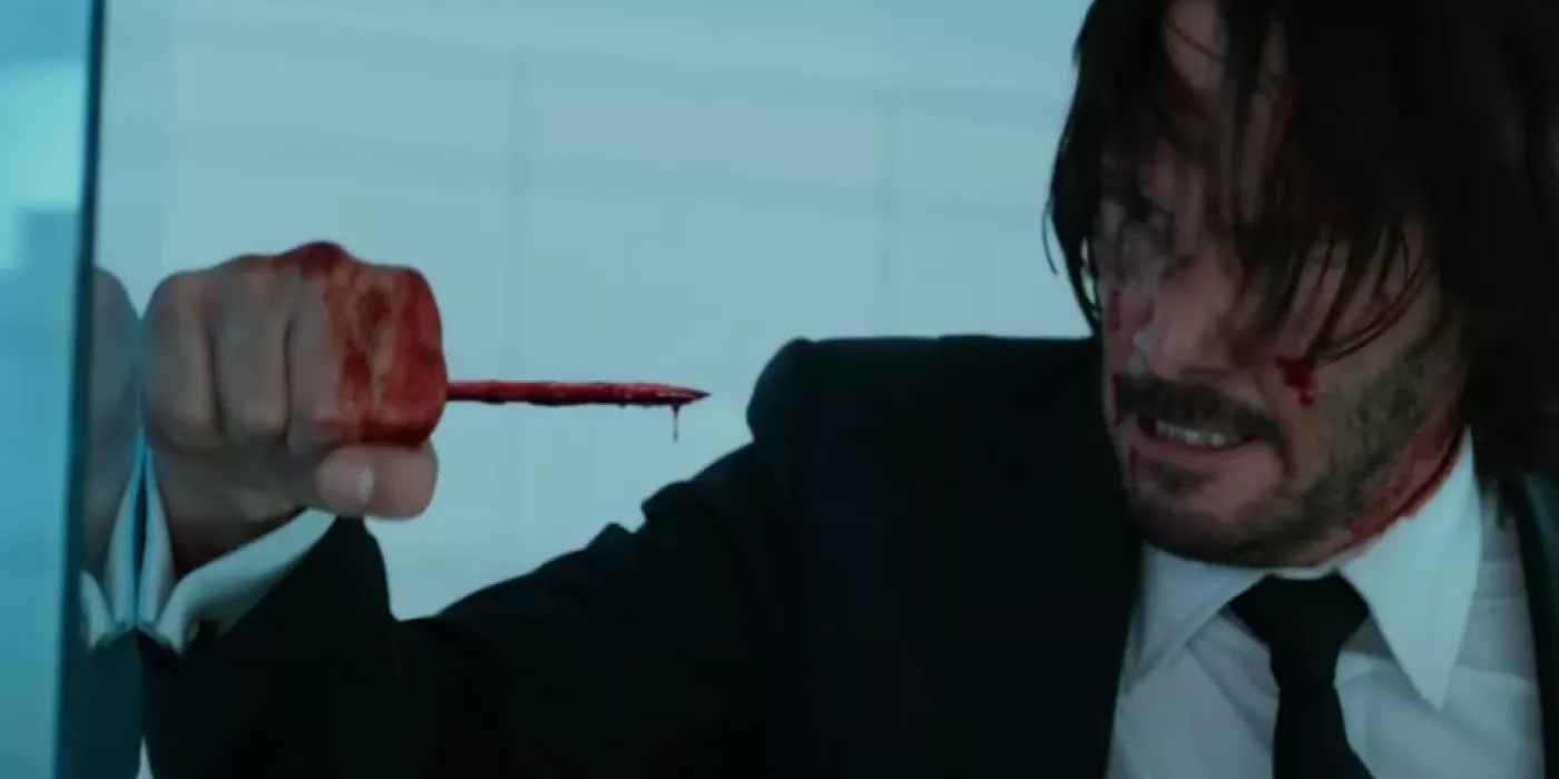 John Wick holds a bloody pencil.