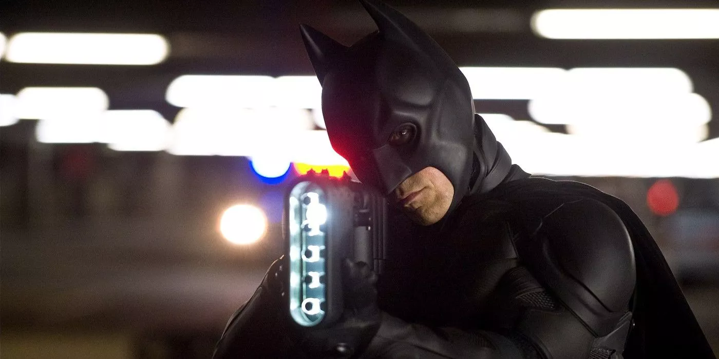 Batman (Christian Bale) aims a stun gun on the streets of Gotham in The Dark Knight Rises