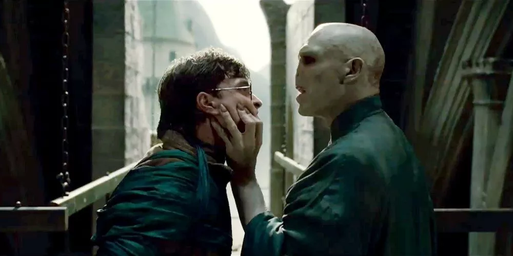 Lord Voldemort agarra el rostro de Harry Potter.