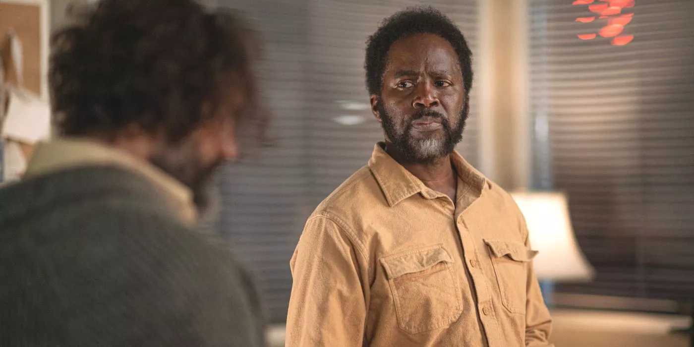 Boyd, played by Harold Perrineau, sits in a yellow shirt at his desk looking at a man in From