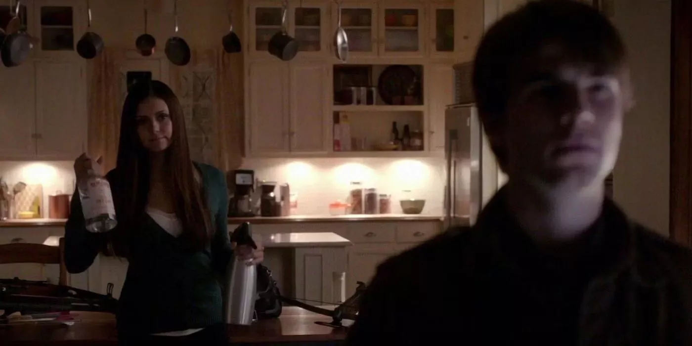 Elena sostiene una botella de alcohol frente a Kol en The Vampire Diaries.