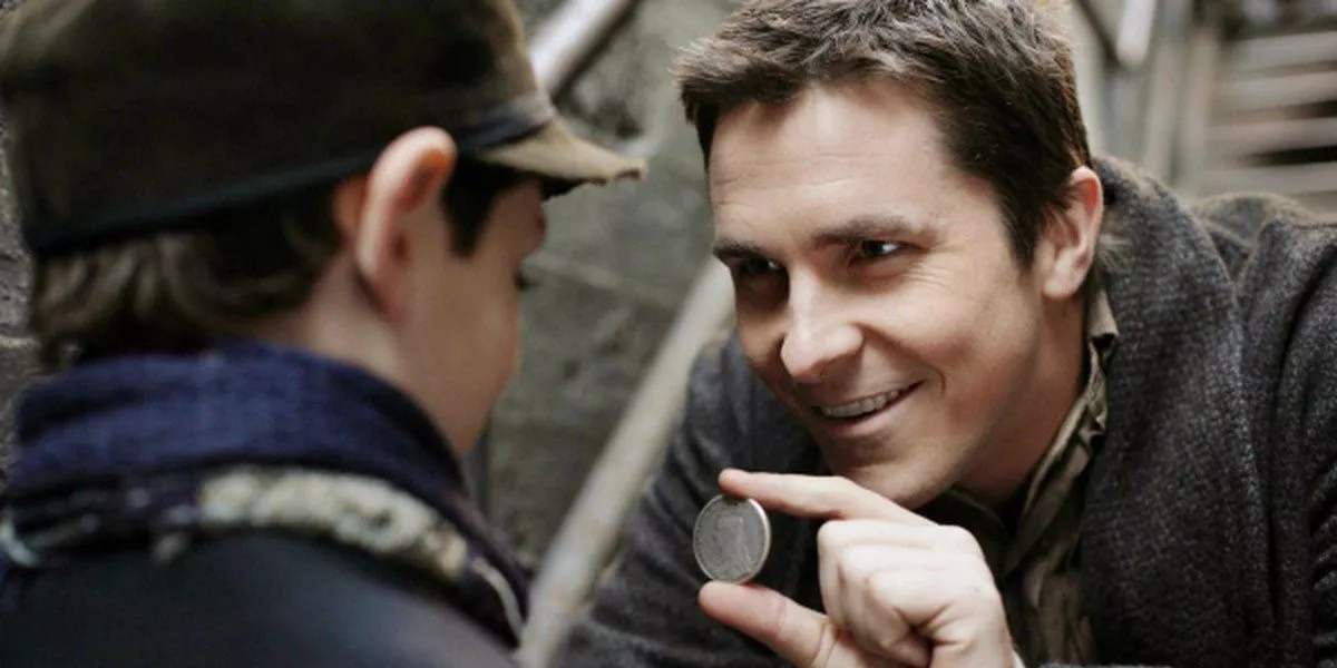 Christian Bale as Alfred Borden in the Prestige, shows a boy a coin