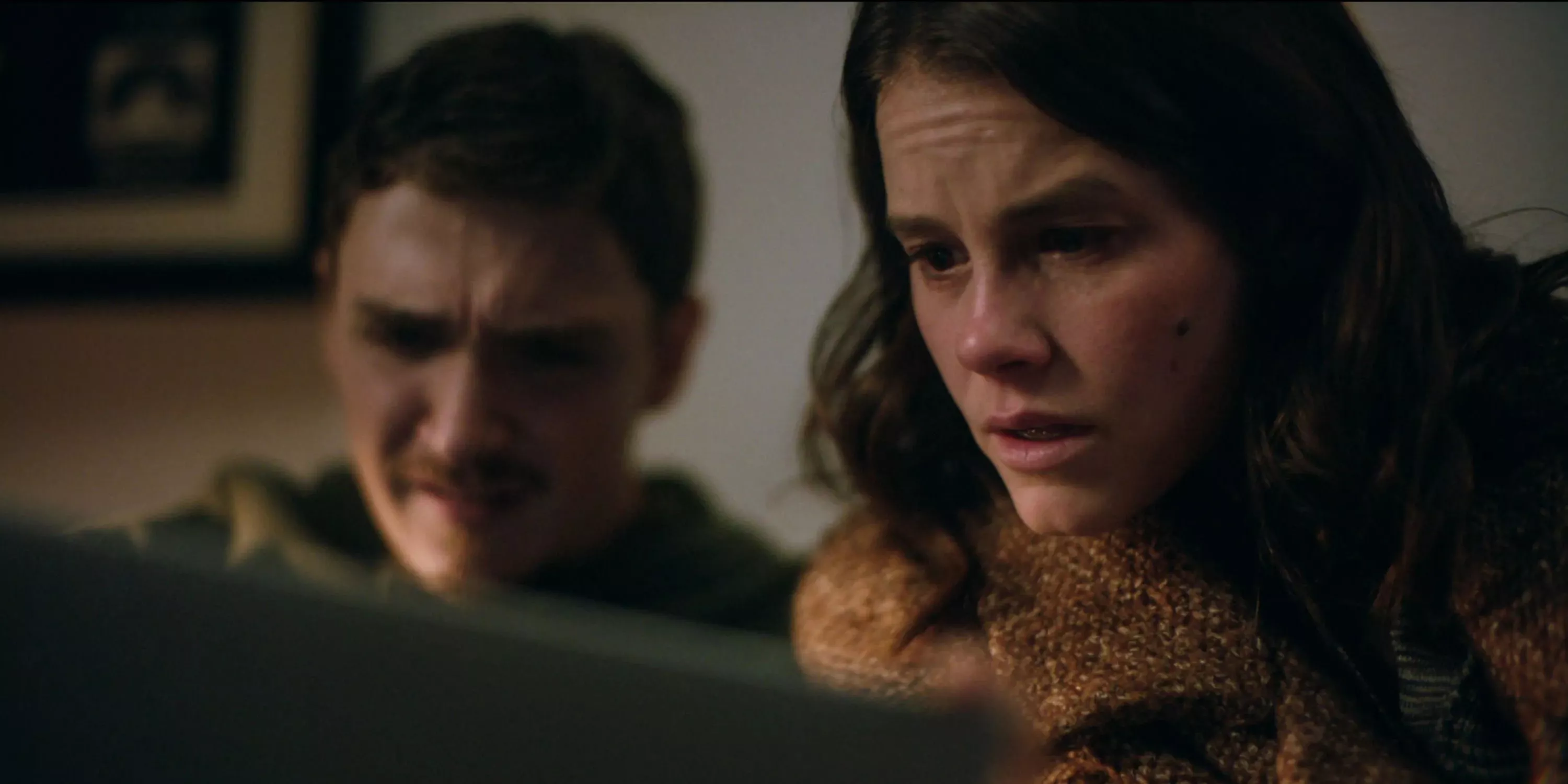 Joel and Rose look scared at a screen in Smile.