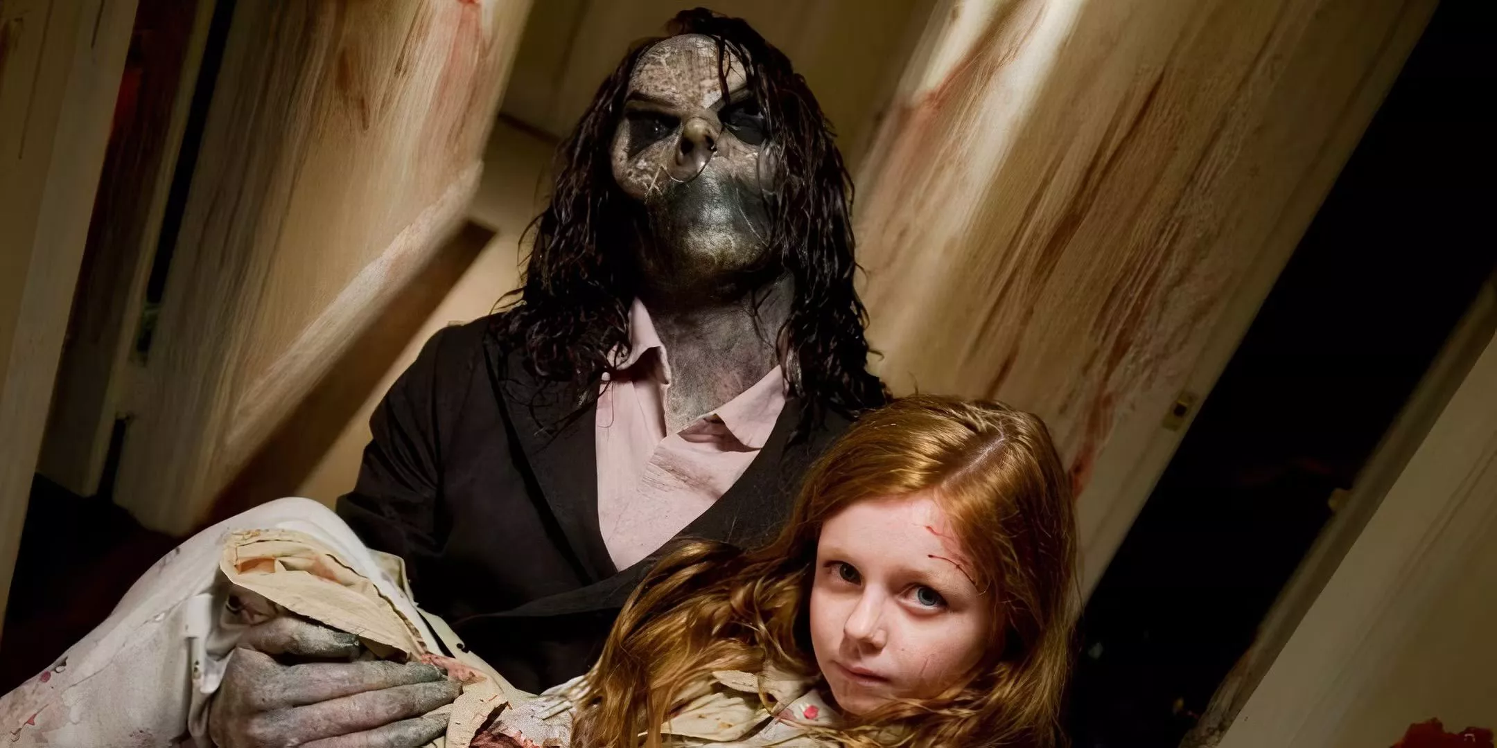 A figure carries a little girl up the stairs in Sinister.