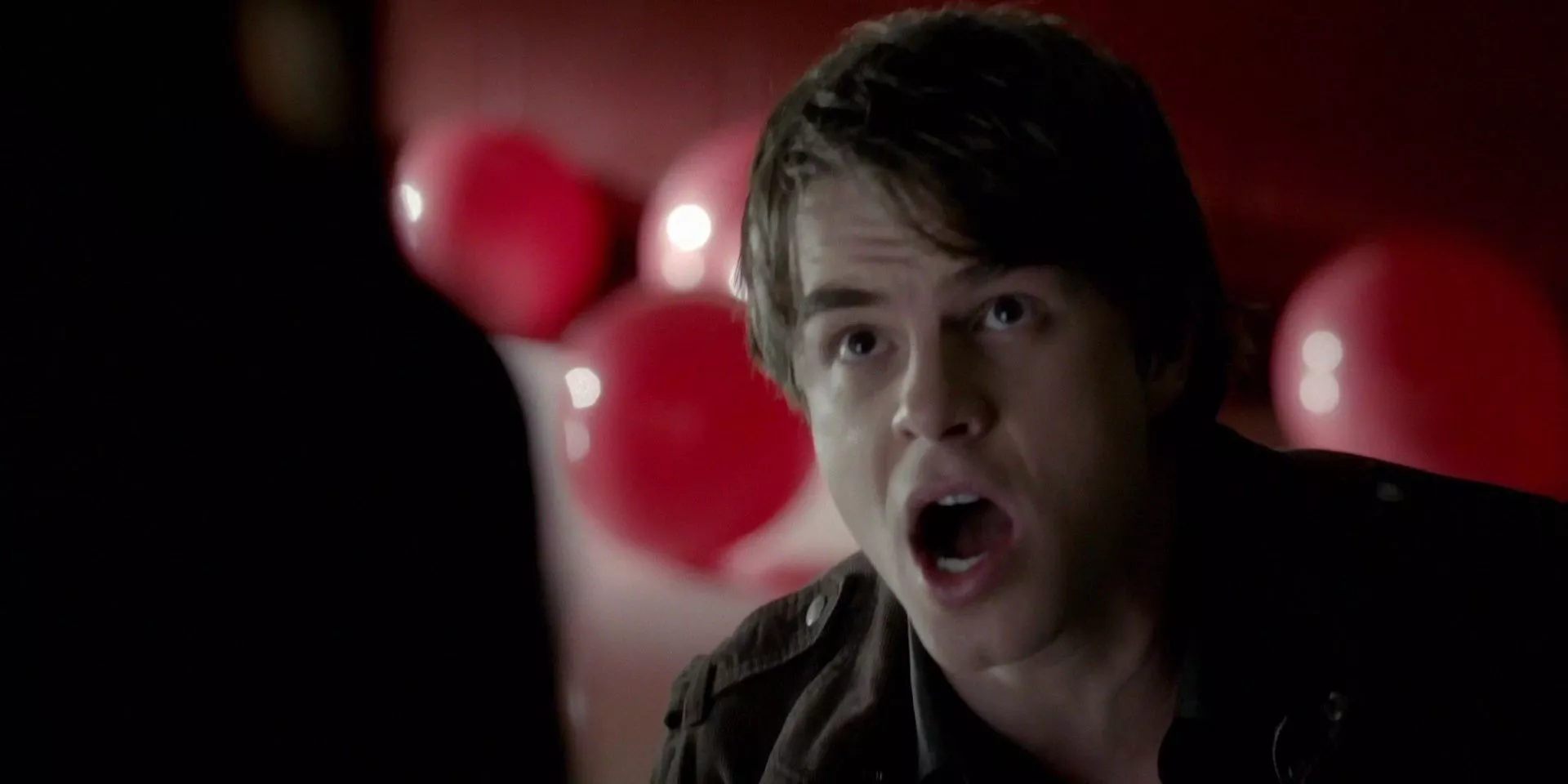 Kol in pain in front of red balloons in The Vampire Diaries.