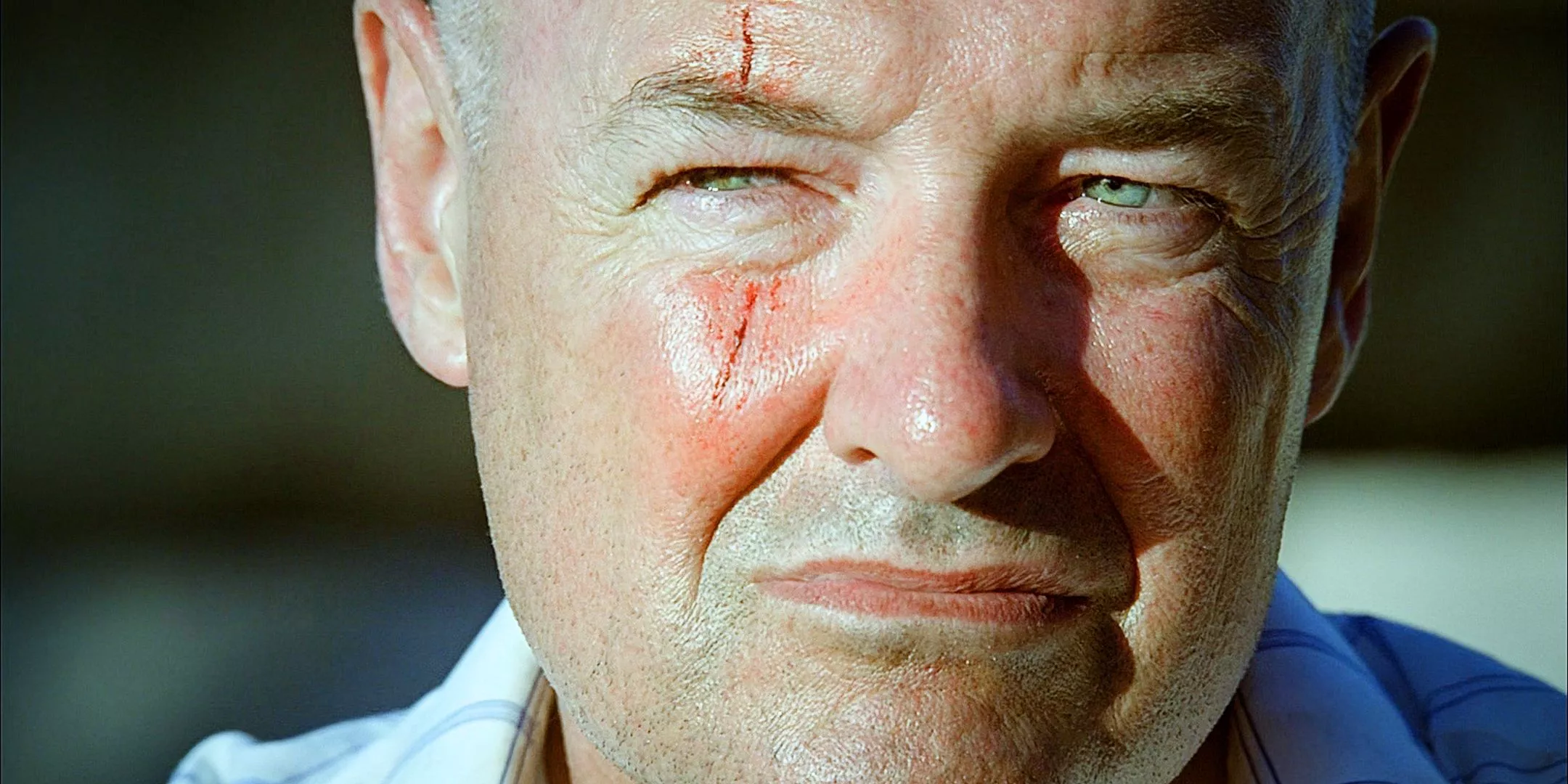 Close up of Terry O'Quinn as John Locke sitting expressionless but also looking very unhinged from the Lost series