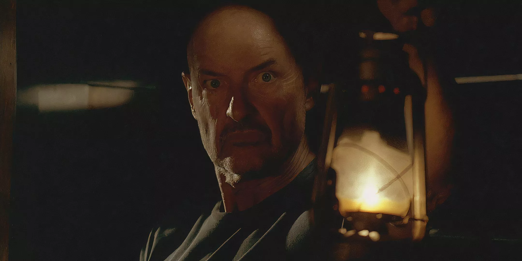 John Locke holding a lantern in the Cabin facing his fears in LOST