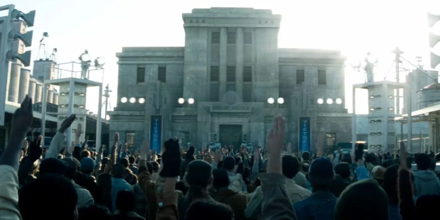 People using the three-fingered salute in front of District 11's Justice Building in The Hunger Games: Catching Fire.