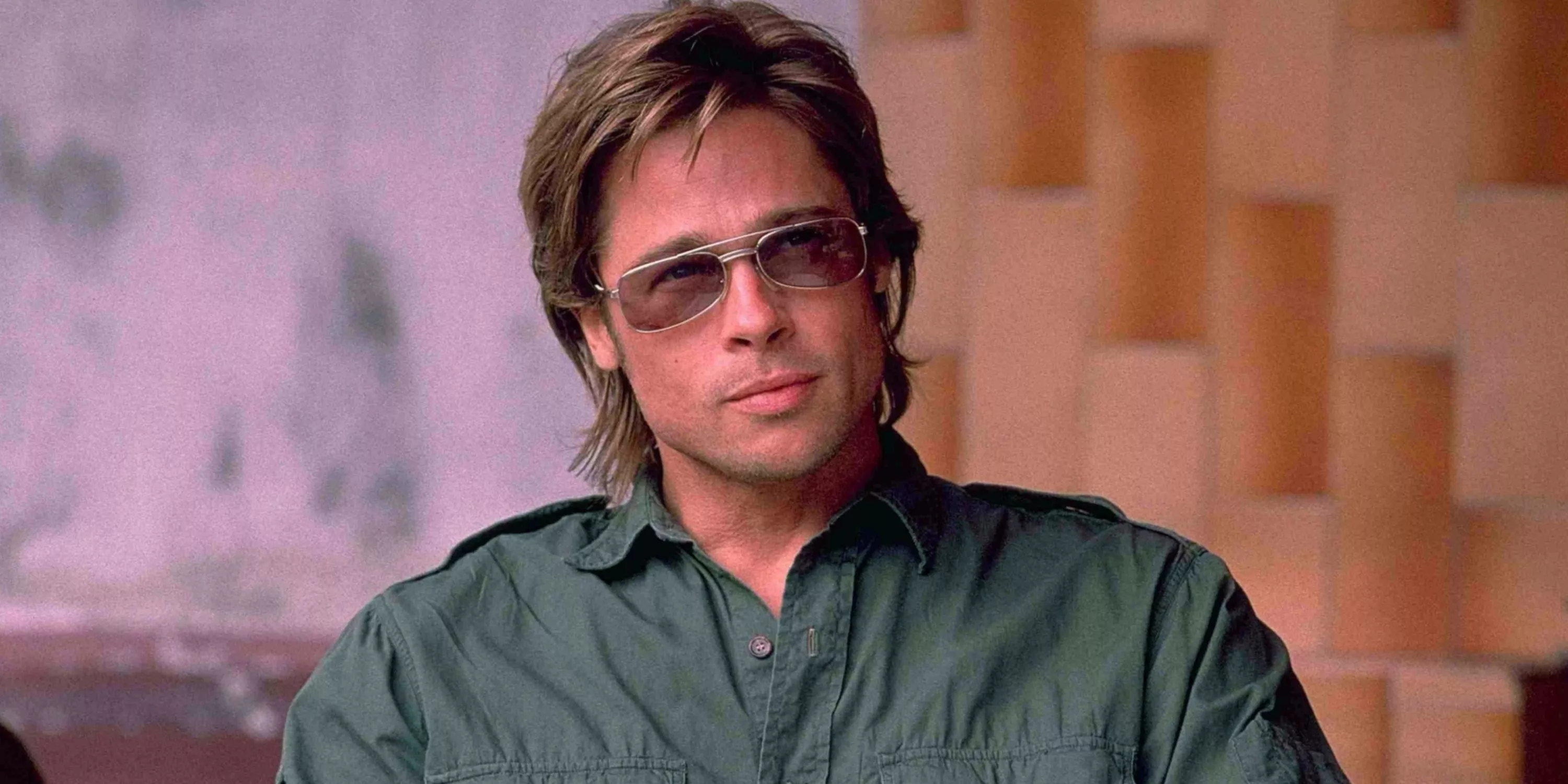 Brad Pitt wears sunglasses sitting at a table outside in Spy Game (2001).