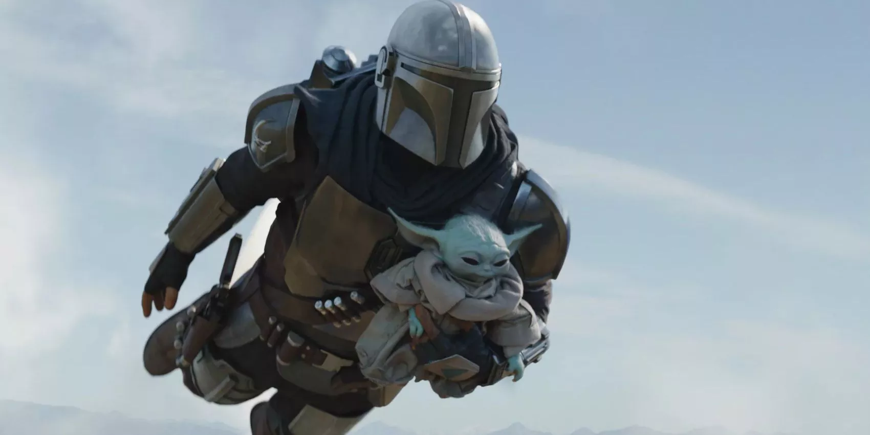 Din Djarin carries Grogu while flying in The Mandalorian