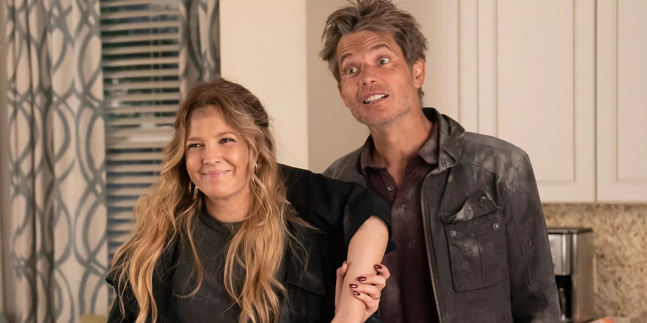 Sheila and joel, dissheveled, holding up a severed arm from Santa Clarita Diet