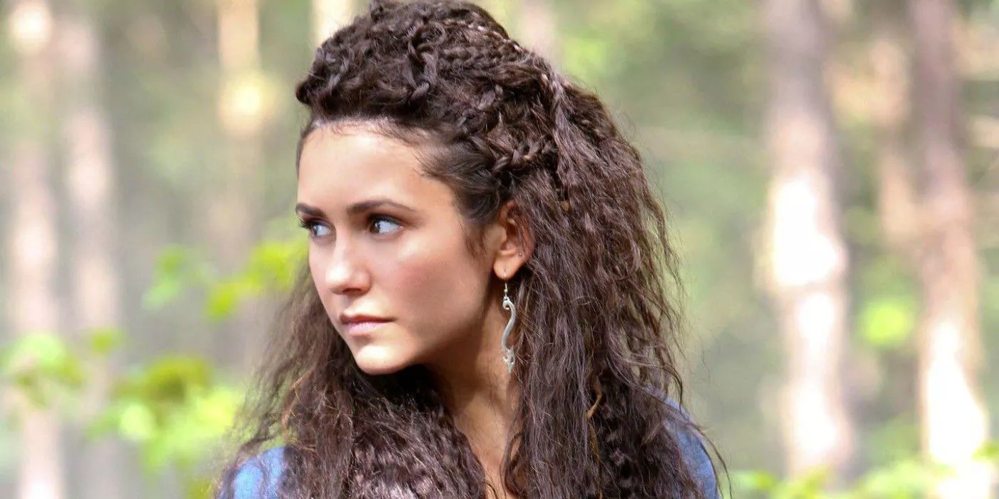 Nina Dobrev como Tatia mirando hacia atrás en un bosque en The Vampire Diaries.