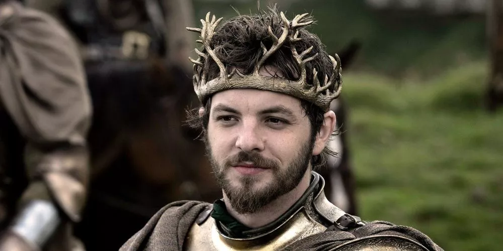 Renly Baratheon lleva una corona y sonríe en Game of Thrones.