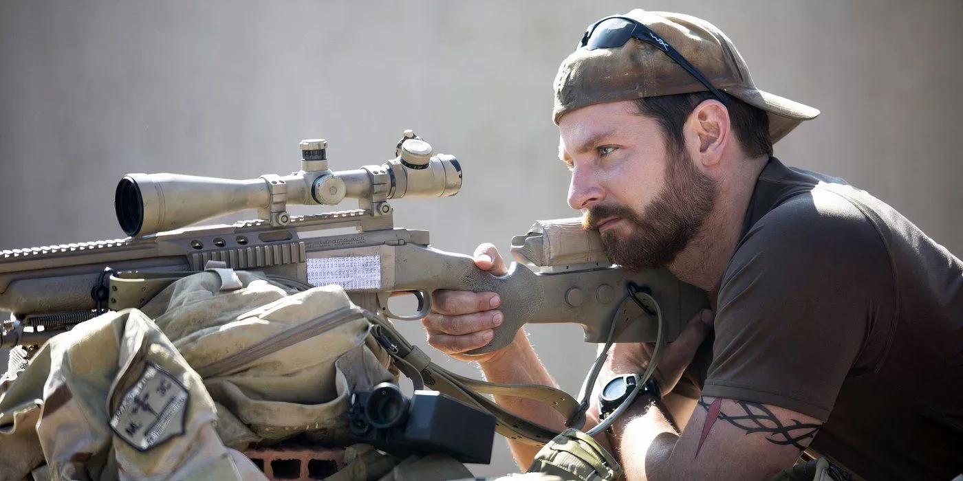 Bradley Cooper como Chris Kyle apuntando su arma en la guerra en American Sniper.