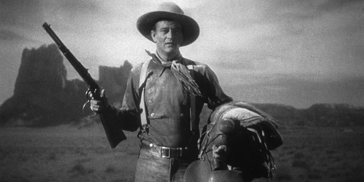 John Wayne holds a rifle and saddle in Stagecoach.