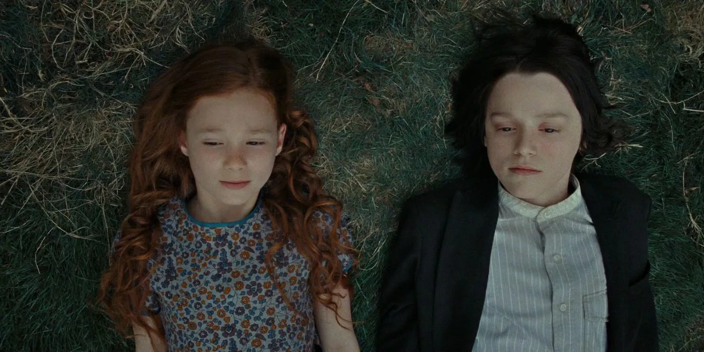 Una joven Lily Evans y Severus Snape yacen lado a lado en la hierba en Harry Potter.