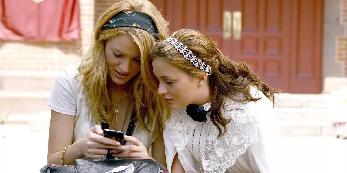 Blair and Serena look into a phone in Gossip Girl.