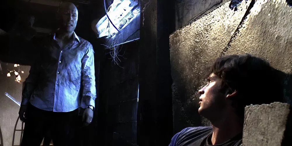 Lex looks down at an injured Clark in a maze in Smallville.