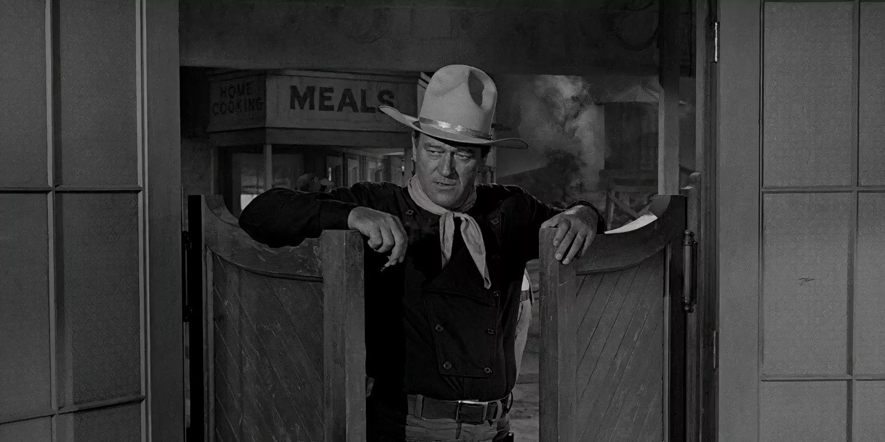 John Wayne enters a saloon through its swinging doors.