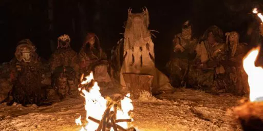 The girls sit in a circle in disguises during a flash-forward in Yellowjackets.