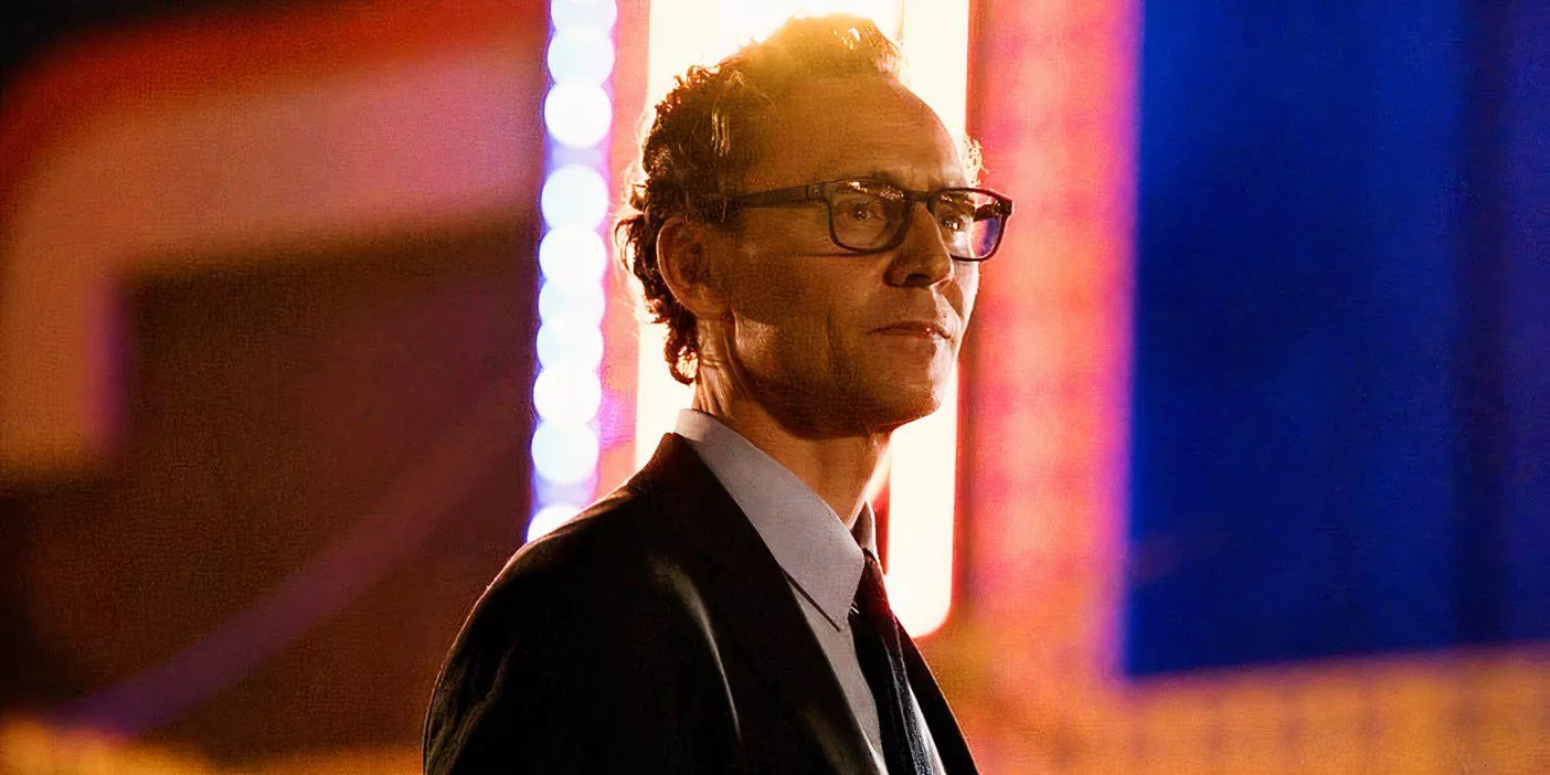 Tom Hiddleston in The Life of Chuck in front of a neon sign